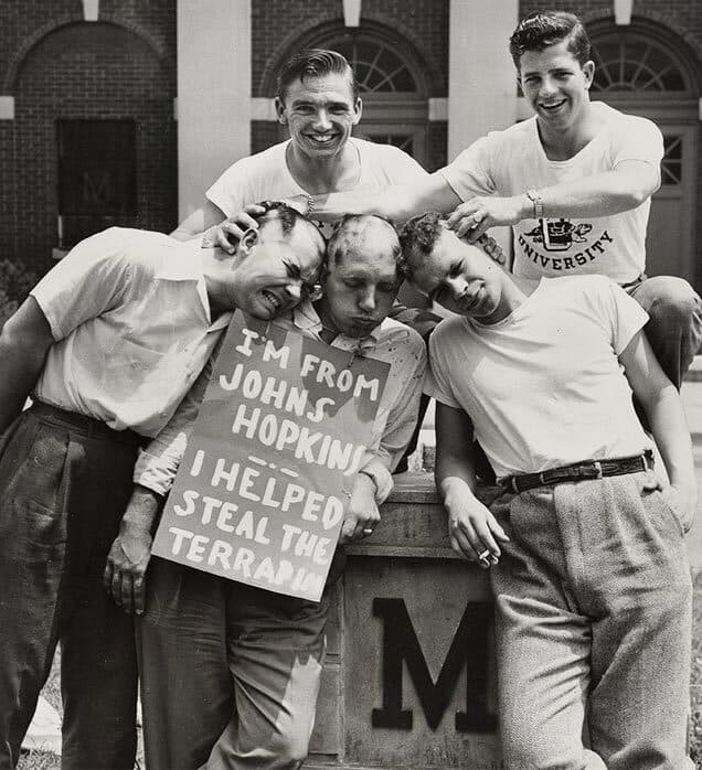 five students pose with sign that reads, "I'm from Johns Hopkins, I helped steal the terrapin"